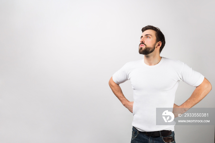 This man is standing in a position of a hero putting his hands on his hips. He is dreaming about better times or the future. That guy looks very serious. Isolated on white background.