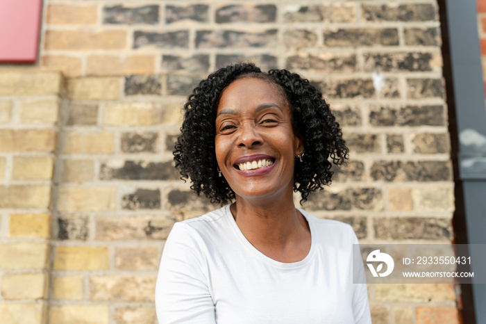 Portrait of smiling woman against brick wall