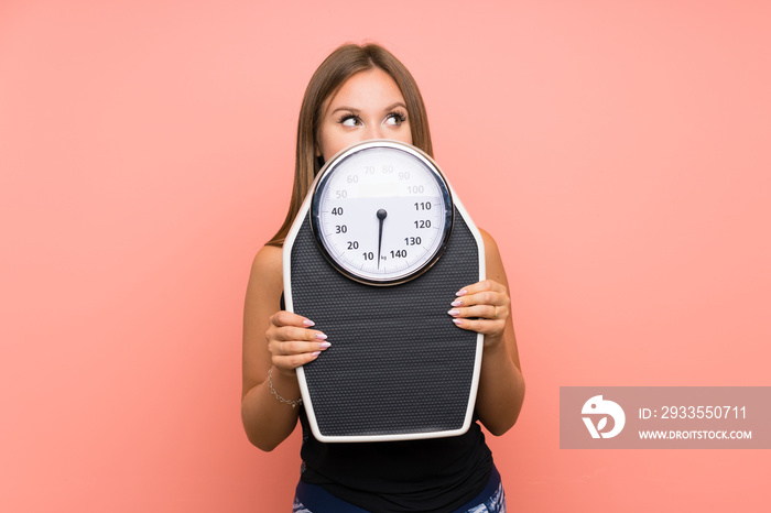 Teenager girl with weighing machine over isolated background