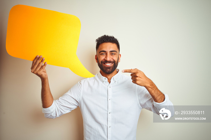 Young arab indian hispanic man holding speech bubble over isolated white background very happy pointing with hand and finger