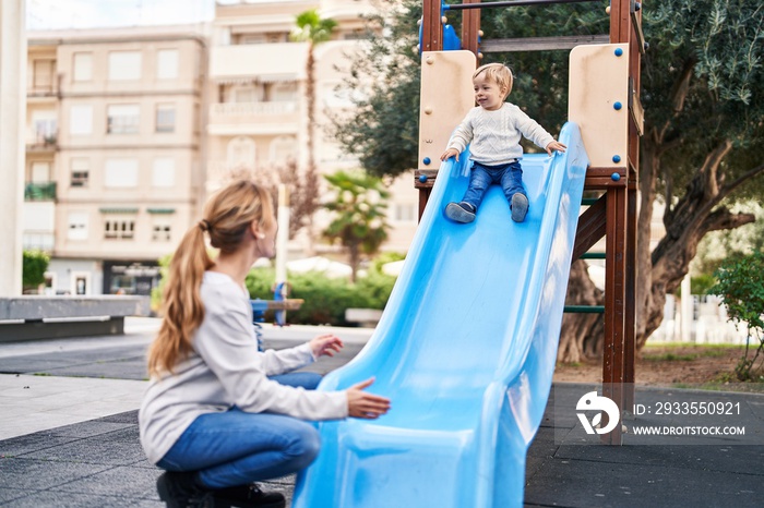 Mother and son playing on slide at park