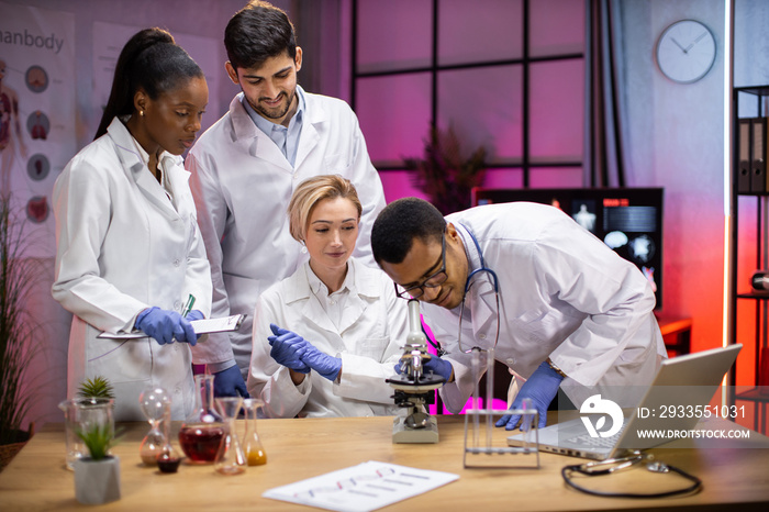 View of modern university research laboratory with multiracial team of young scientists performing experiments on lab equipment.