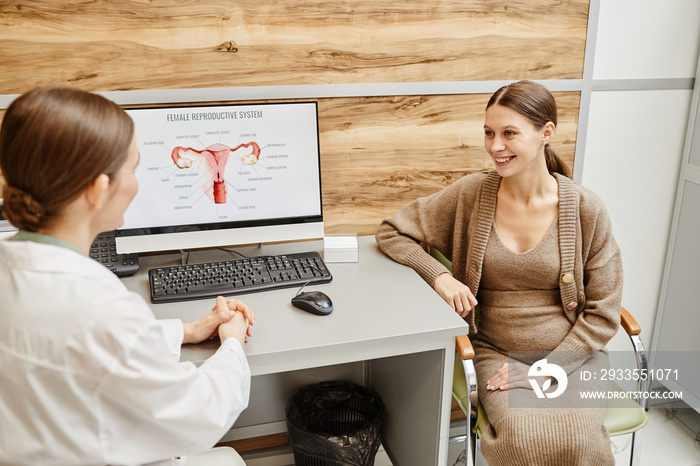 Portrait of young pregnant woman smiling happily during consultation with ob gyn in modern fertility clinic