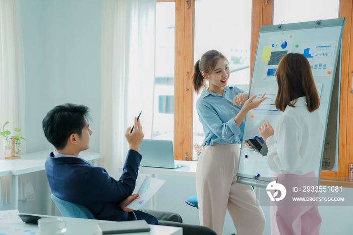 A group of cheerful modern Asian businessmen working together. Sit at a table discussing new project discovery solutions to increase effective communication ideas. chart on whiteboard