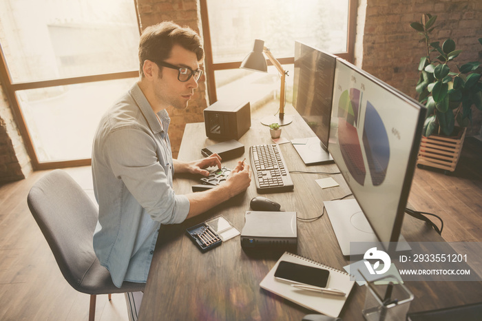 Profile side photo of focused guy sit desk look monitor computer screen see charts funds statistics data work with hardware in modern home office