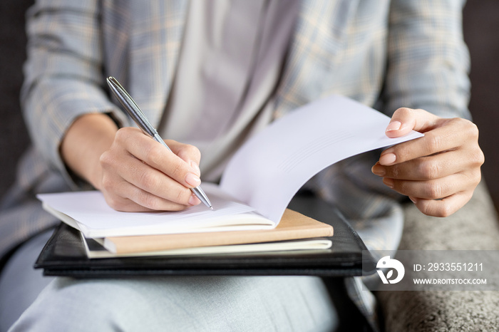 Contemporary young teacher with pen checking paper of one of students