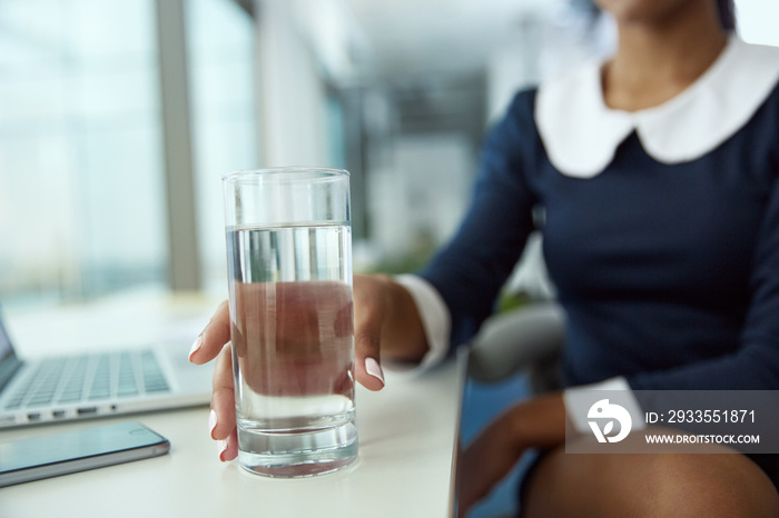 Cup with water in hand of african businesswoman