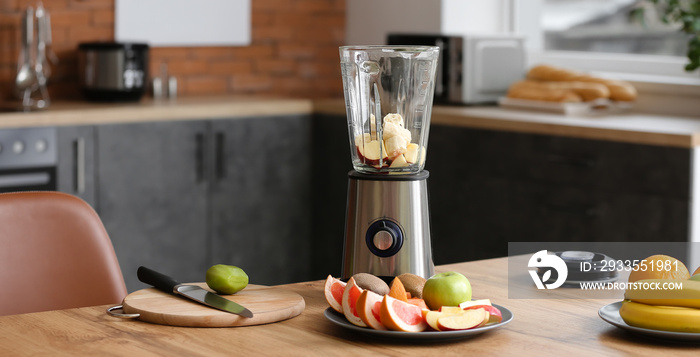 Modern blender with fresh fruits and cutting board on table in kitchen