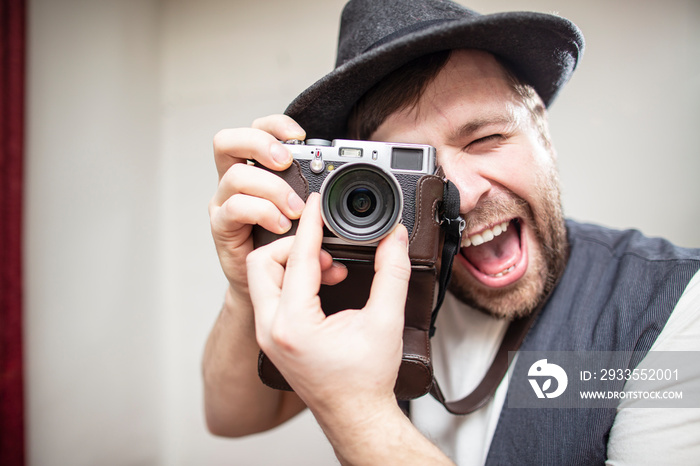 Positive photographer, in a felt hat, takes a picture on the camera, with copy space.