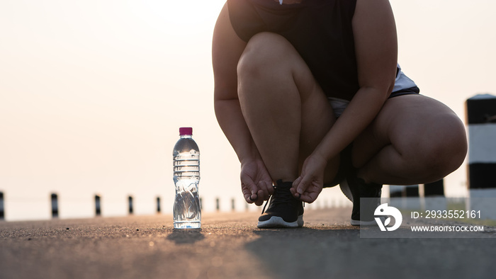 Running shoes - closeup of woman tying shoe laces. She is getting ready to jogging in the early morning sunlight. concept of losing weight with exercise. with copy space.