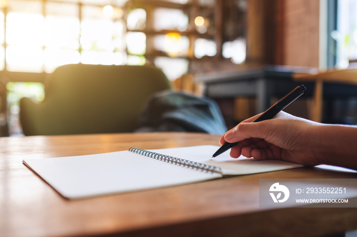 Closeup image of a woman writing on a blank notebook on the table