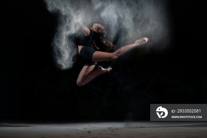 Dancing girl in a jump with dust powder