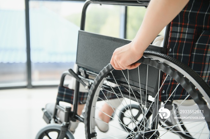 Woman in wheelchair’s hand on wheel close up