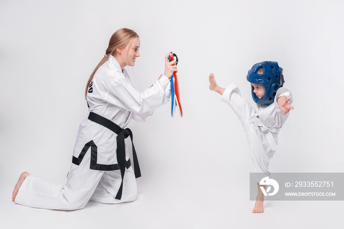 Mother her little son practicing martial arts over white background.