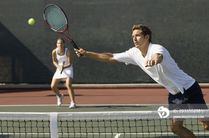 View of doubles player hitting tennis ball with forehand near net on court