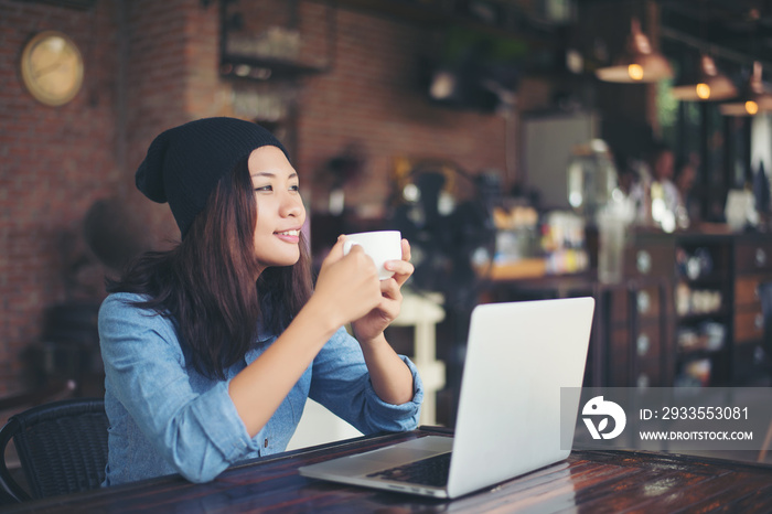 Beautiful young hipster woman sitting in a coffee shop, holding