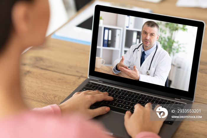 Unrecognizable female patient having online video call with doctor on laptop, indoors