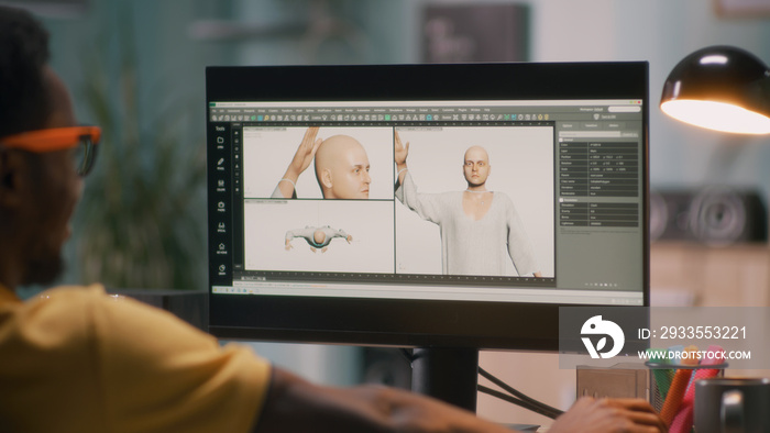 Black guy creating 3D model of bald human for movie or video game on computer during work in home office