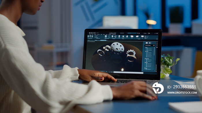 Tired african designer engineer analyzing new prototype of 3D model of industry product, working overtime. Industrial female worker studying gears idea on laptop showing cad software on device display