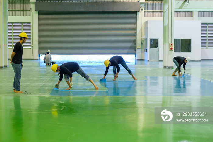 Construction workers are using trowel spreading epoxy putty for Self-leveling method of epoxy floor finishing work