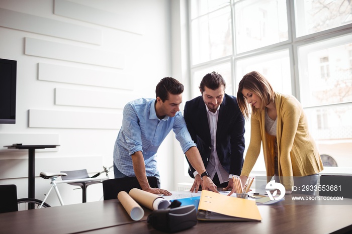 Businessman explaining blueprint to coworkers