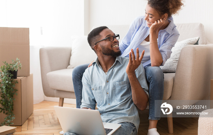 African American Couple Talking Using Laptop Sitting In New Flat