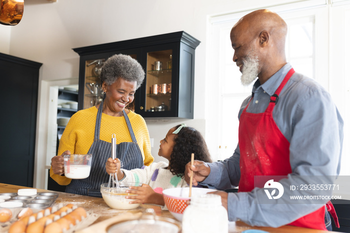 Image of happy african american grandparents and granddaughter baking in kitchen