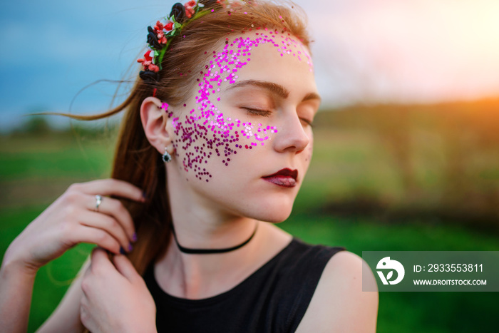 A young beautiful woman with a violet shine on her face standing on the grass and looking right