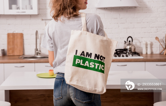 Young girl holding a cloth bag. At the kitchen. I am not plastic. Campaign to reduce the use of plastic bags. Zero waste