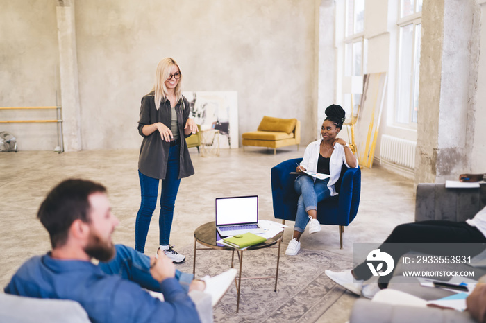 Cheerful modern colleagues discussing job in spacious office