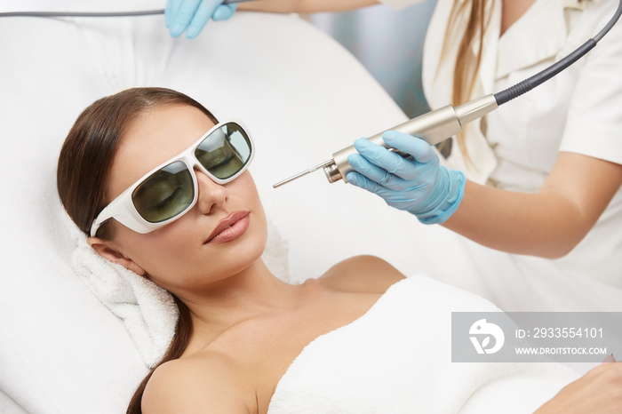 woman in protection glasses receiving facial treatment with laser