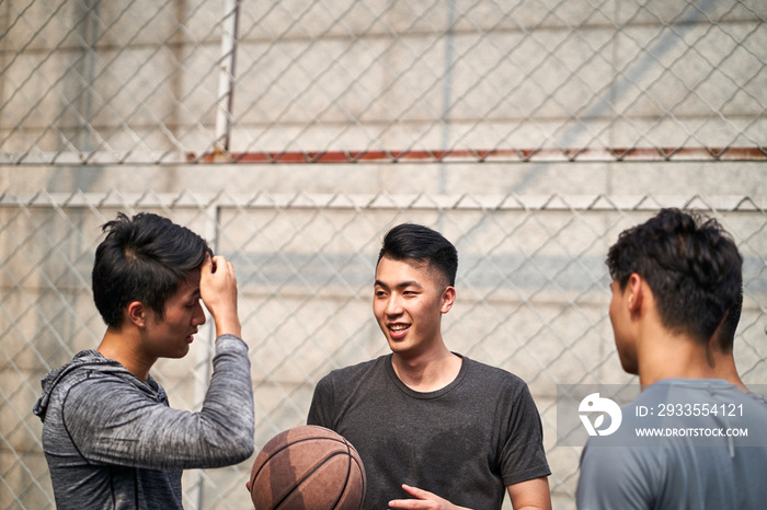 young asian basketball players chatting on outdoor court