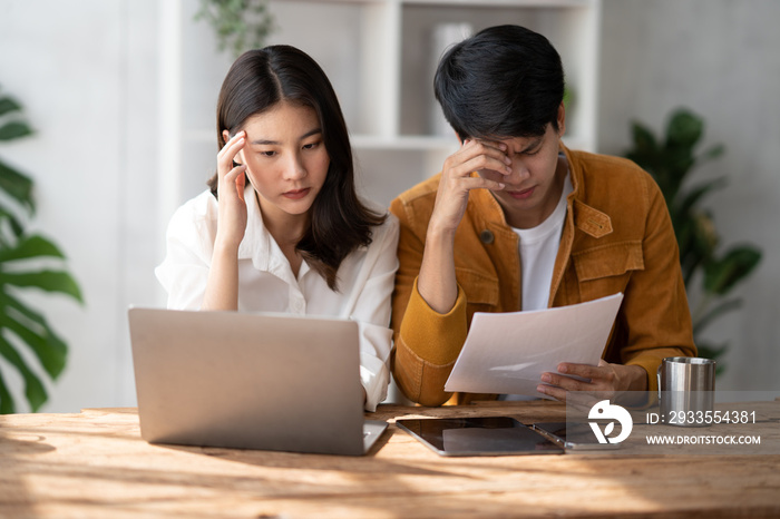 Stress, anxiety and worry with a young couple struggling with finance, debt and the home budget in the living room.