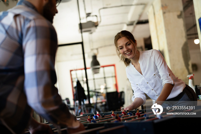 Colleagues having fun at work. Businessman and businesswoman playing table soccer..