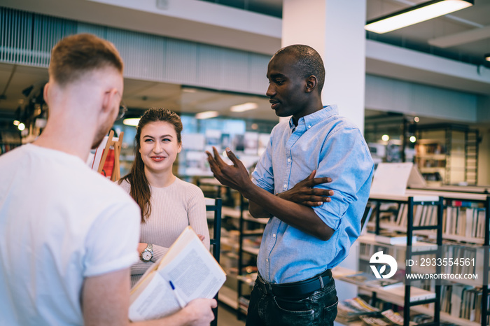 Multiethnic team of students during conversation in library