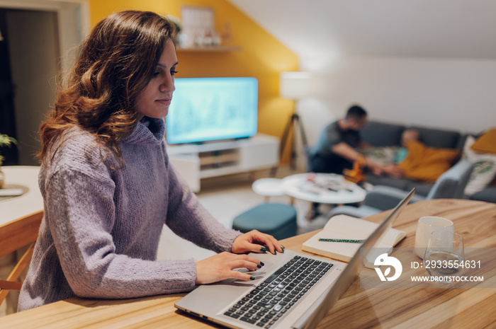 Hispanic businesswoman working from home on her laptop sitting in the kitchen