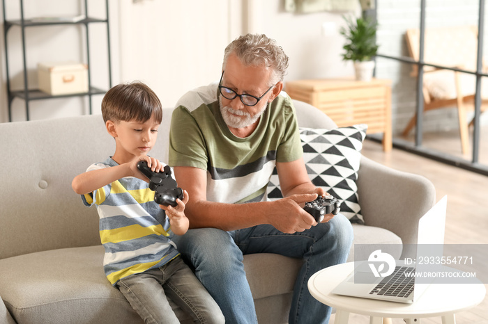 Little boy with his grandfather playing video game at home