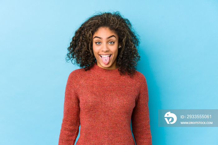 Young african american curly hair woman funny and friendly sticking out tongue.