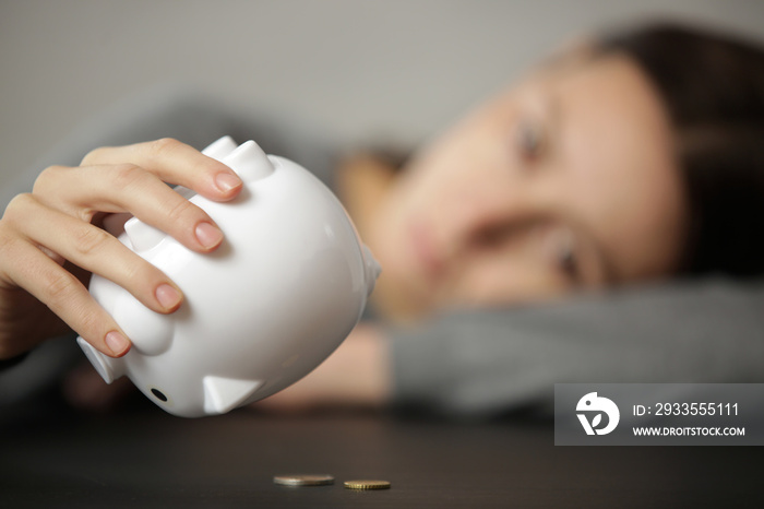 Unhappy woman shaking an empty piggy bank