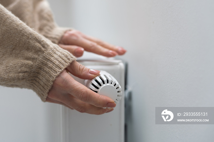 Woman holding temperature knob of heating radiator