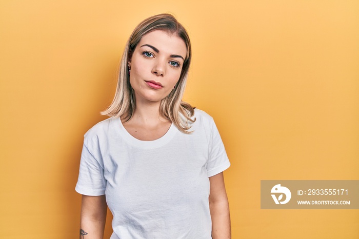 Beautiful caucasian woman wearing casual white t shirt relaxed with serious expression on face. simple and natural looking at the camera.