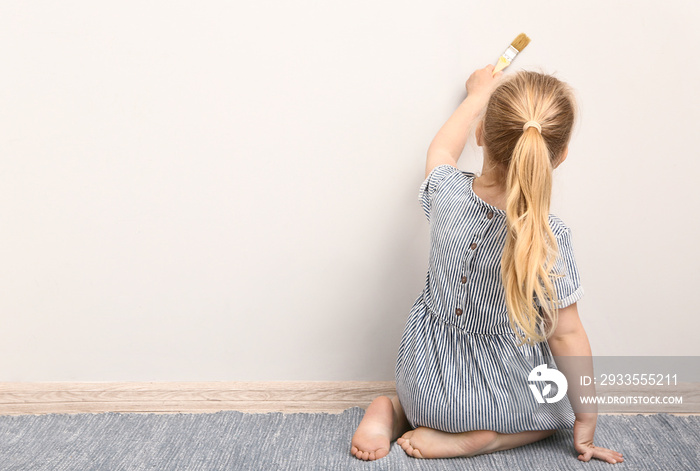 Little girl painting on light wall