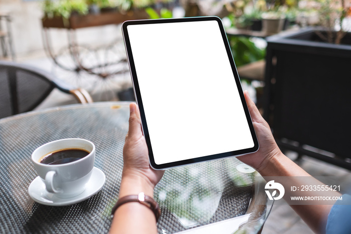 Mockup image of a woman holding digital tablet with blank white desktop screen in the outdoors cafe