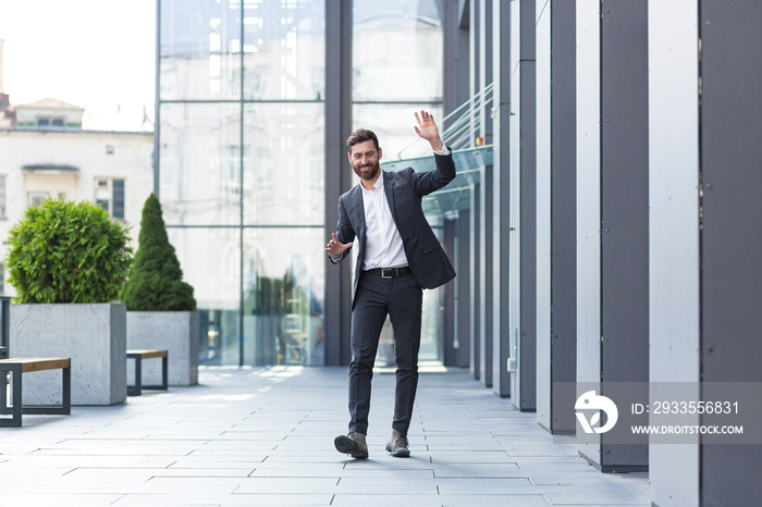 Cheerful happy business man dancing walk the city street background a modern office building outside, outdoors Funny successful businessman in suit celebtes victory