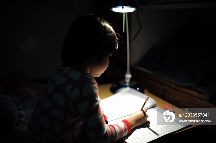 Portrait of little Asian girls doing her homework under the lighting lamp