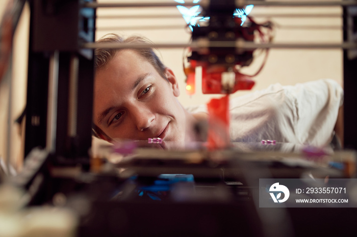 Glad young man watching 3D printing process