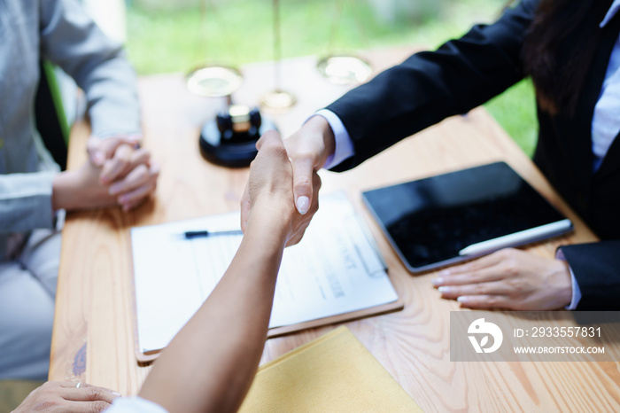 Law, consultation, agreement, contract, lawyer or  attorney shakes hands to agree on the client’s offer to be hired to fight the parties in court.