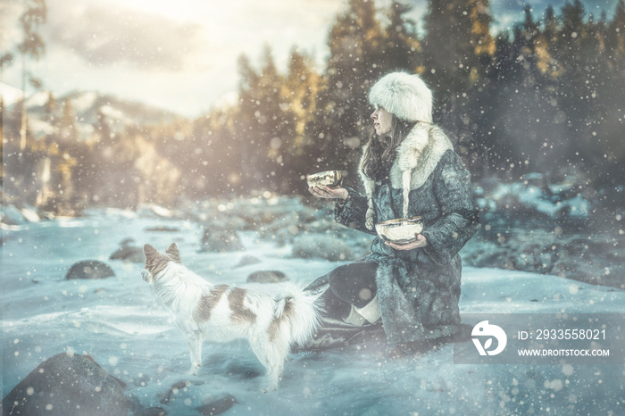 Beautiful shamanic girl playing on tibetian bowl in the nature.