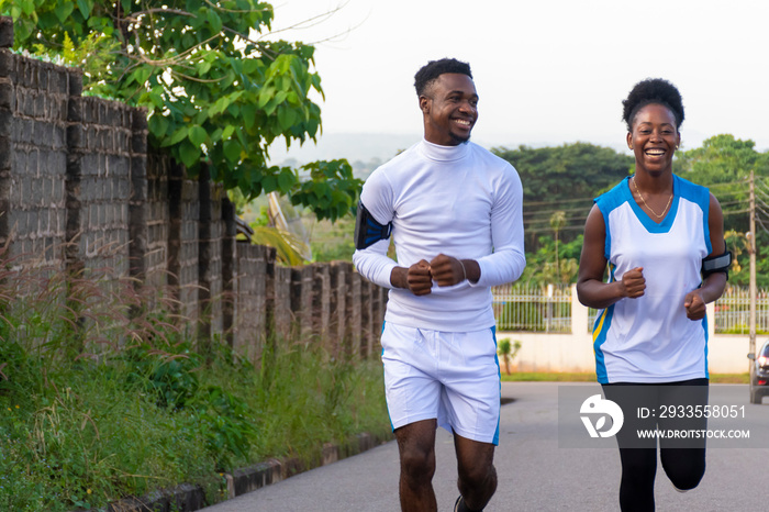 young black man and woman jogging together, having fun and laughing