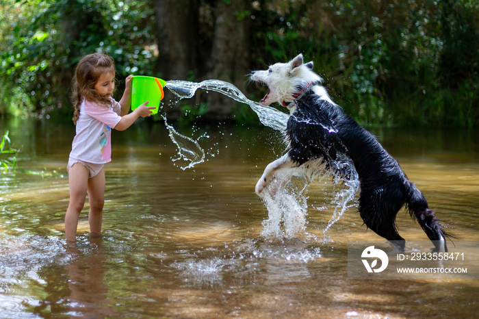 Little girl throwing water with a bucket into the river. Girl with swimsuit and t-shirt. Children’s photo in summer.